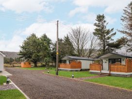 A gravel driveway leading to two small cabins with wooden fences surrounded by grass and trees at Benone Cabin Magilligan near Castlerock