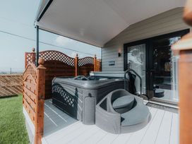An outdoor hot tub on a covered wooden deck with lattice fencing at Benone Cabin in Magilligan near Castlerock