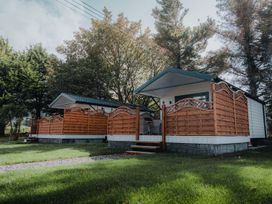 Two small cabins with wooden fences and steps surrounded by grass and trees at Benone Cabin in Magilligan near Castlerock