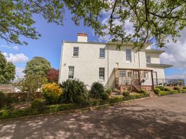 The exterior of a two-story house with white walls and multiple windows surrounded by plants and trees at Buckland House and Annex Lower Durston near Taunton