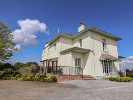 An exterior view of a two-story house with a gravel driveway and landscaped bushes at Buckland House and Annex in Lower Durston near Taunton