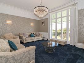 A sitting room with upholstered sofas a round coffee table and glass doors leading outside at Buckland House and Annex in Lower Durston near Taunton