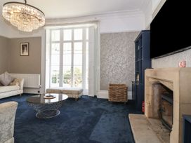 A living room with a blue carpet a stone fireplace and large window at Buckland House and Annex Lower Durston near Taunton