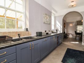 A kitchen with blue cabinets a sink microwave and an archway leading to a dining area at Buckland House and Annex in Lower Durston near Taunton