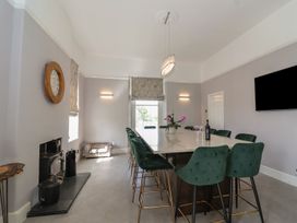 A dining room with a long table surrounded by green chairs a fireplace and a wall mounted tv at Buckland House and Annex in Lower Durston near Taunton
