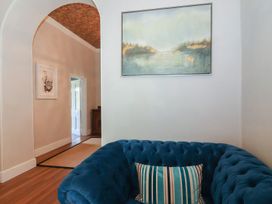 A blue tufted sofa with a striped pillow under a painting beside an archway in a room at Buckland House and Annex in Lower Durston near Taunton