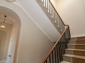 A staircase with wooden handrail and black balusters next to an arched doorway and a hanging light at Buckland House and Annex in Lower Durston near Taunton