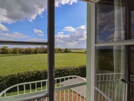 A view of green fields and trees through an open window with white frames and a white railing at Buckland House and Annex in Lower Durston near Taunton
