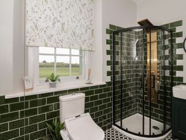 A bathroom with a white toilet shower enclosure with green tiles and a window with patterned blind at Buckland House and Annex Lower Durston near Taunton