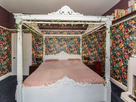 A bedroom with a white canopy bed and colorful floral wallpaper at Buckland House and Annex in Lower Durston near Taunton