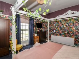 A bedroom with a four-poster bed and colorful floral wallpaper at Buckland House and Annex in Lower Durston near Taunton