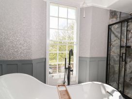 A bathroom with a freestanding bathtub near a large window and a glass shower enclosure at Buckland House and Annex in Lower Durston near Taunton