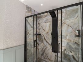 A bathroom shower area with marble walls and black framed glass doors at Buckland House and Annex in Lower Durston near Taunton