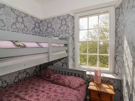 A small bedroom with a bunk bed and a bedside table with a lamp by a window at Buckland House and Annex in Lower Durston near Taunton