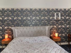 A bedroom with a tufted headboard bed floral quilt and animal patterned wallpaper at Buckland House and Annex Lower Durston near Taunton