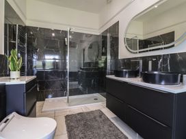 A bathroom with black marble tiled walls a glass shower black double sinks and a white toilet at Buckland House and Annex in Lower Durston near Taunton