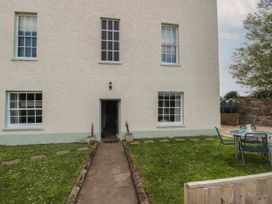 The exterior of a house with four windows a door a pathway two plants on either side of the door and a round table with three chairs on a lawn at Buckland House and Annex Lower Durston near Taunton