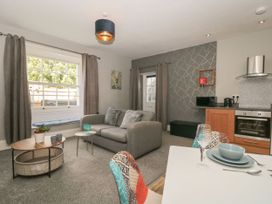 An open plan living room and kitchen area with a grey sofa curtains coffee tables and dining table at Buckland House and Annex Lower Durston near Taunton