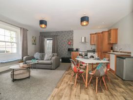 An open plan living room and kitchen with a gray sofa a dining table with colorful chairs and wooden kitchen cabinets at Buckland House and Annex Lower Durston near Taunton