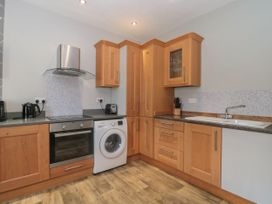 A kitchen with wooden cabinets a washing machine an oven and a sink at Buckland House and Annex in Lower Durston near Taunton