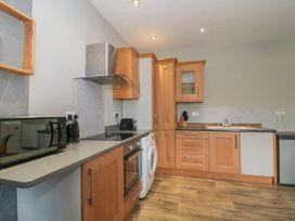 A kitchen with wooden cabinets an oven microwave washing machine and a sink at Buckland House and Annex Lower Durston near Taunton