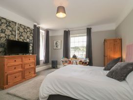 A bedroom with a bed two chairs a small table a wooden dresser with a television and a wooden wardrobe at Buckland House and Annex in Lower Durston near Taunton
