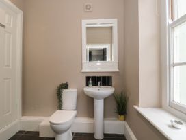 A bathroom with a toilet and pedestal sink under a mirror and a window on the side at Buckland House and Annex Lower Durston near Taunton