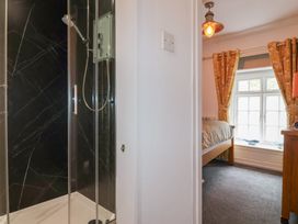 A bathroom with a shower next to a bedroom with a bed and window with curtains at Teana Cottage in Polperro