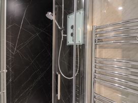 A shower enclosure with a handheld showerhead and a chrome towel radiator in a bathroom at Teana Cottage in Polperro