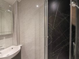 A bathroom with a white sink and a glass door shower with black marble walls at Teana Cottage Polperro