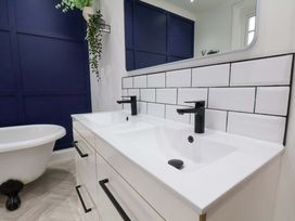 A bathroom with a sink, tub, and wall tiles at 59 Moorland Road Scarborough