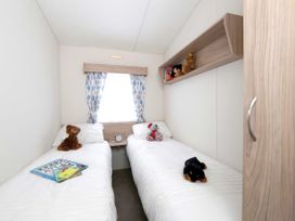 A bedroom with twin beds and a shelf of toys at Tide’s Reach - Hayling Island