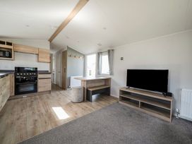 A living room with a kitchen unit and television at Billy’s Way - Hayling Island Holiday Park