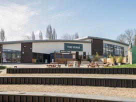 An outdoor seating area with picnic tables and a building labeled The Venue at Billing Aquadrome Holiday Park