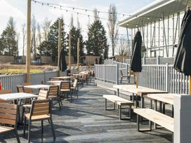 An outdoor seating area with tables, chairs, benches, umbrellas, and string lights at Ripples & Reeds - Billing Aquadrome in Billing Aquadrome Holiday Park