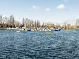 A lake with inflatable water park equipment and cabins surrounded by trees at Billing Aquadrome Holiday Park