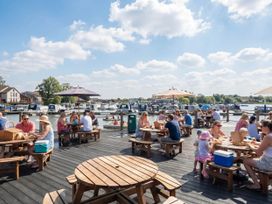 A dock area with seating and people dining at Kingfisher Caravan - Billing Aquadrome