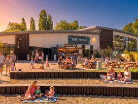 An outdoor area with people sitting at tables and children playing at The Venue in Billing Aquadrome Holiday Park