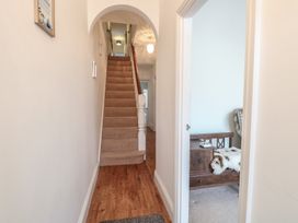 A hallway with wooden flooring leading to carpeted stairs and a partially visible room with a wooden bench and a fur throw at 34 North Denes Road in Great Yarmouth