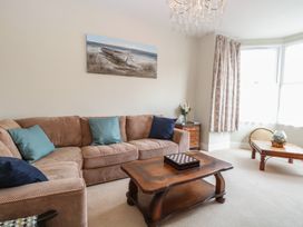 A living room with a beige sofa and blue cushions a wooden coffee table and a side table with flowers at 34 North Denes Road in Great Yarmouth