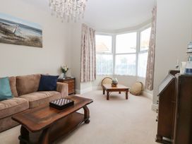 A living room with a brown sofa cushions wooden coffee tables and a bay window at 34 North Denes Road Great Yarmouth