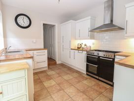 A kitchen with white cabinets wooden countertops a black double oven and a wall clock at 34 North Denes Road Great Yarmouth