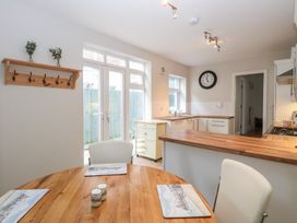 A kitchen with wooden countertops a round wooden dining table white chairs placemats salt and pepper shakers wall clock and glass doors at 34 North Denes Road in Great Yarmouth