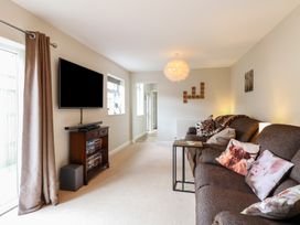 A living room with a sofa with animal print cushions a wall-mounted television and a wooden cabinet at 34 North Denes Road in Great Yarmouth