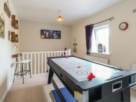 A game room with an air hockey table a bar stool a window with curtains and wall decorations at 34 North Denes Road in Great Yarmouth