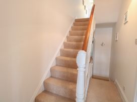 A carpeted staircase with a wooden handrail and white balusters in a narrow hallway at 34 North Denes Road Great Yarmouth