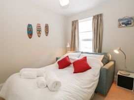 A bedroom with a bed with white bedding red pillows and rolled towels next to a window and lamps at 34 North Denes Road in Great Yarmouth