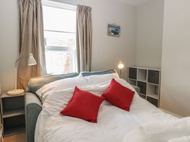 A bedroom with a sofa bed opened with white bedding and red cushions near a window at 34 North Denes Road in Great Yarmouth