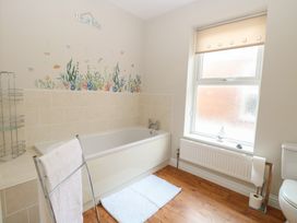 A bathroom with a bathtub wall tiles a window radiator towel rail and toilet at 34 North Denes Road Great Yarmouth
