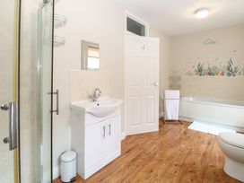 A bathroom with a shower, sink, bathtub with sea life wall decals, towel rack, and wooden floor at 34 North Denes Road in Great Yarmouth